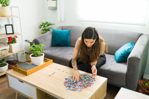 Frau sitzt am Tisch und puzzelt