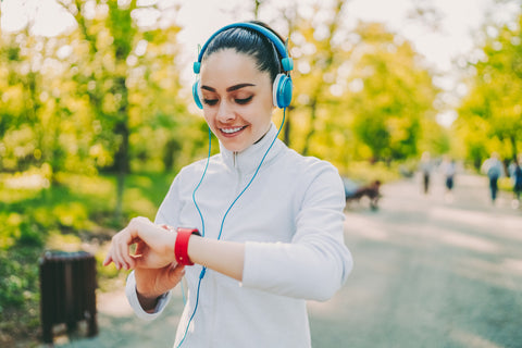 Fitness-Tracker Gesundheit: Frau schaut beim Joggen auf ihre Fitnessuhr